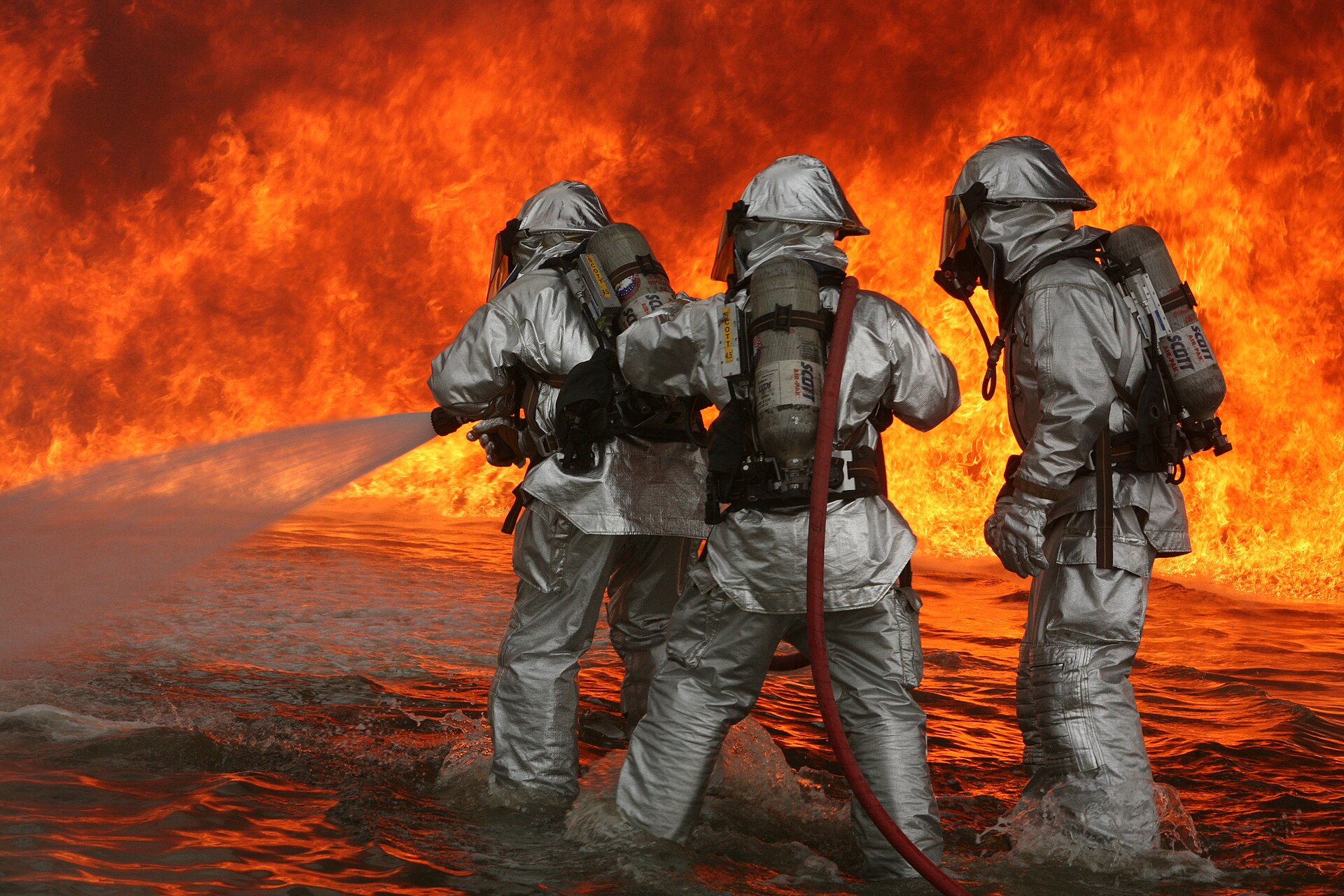Firefighters battle a wildfire while standing in water, demonstrating the dedication of frontline workers.