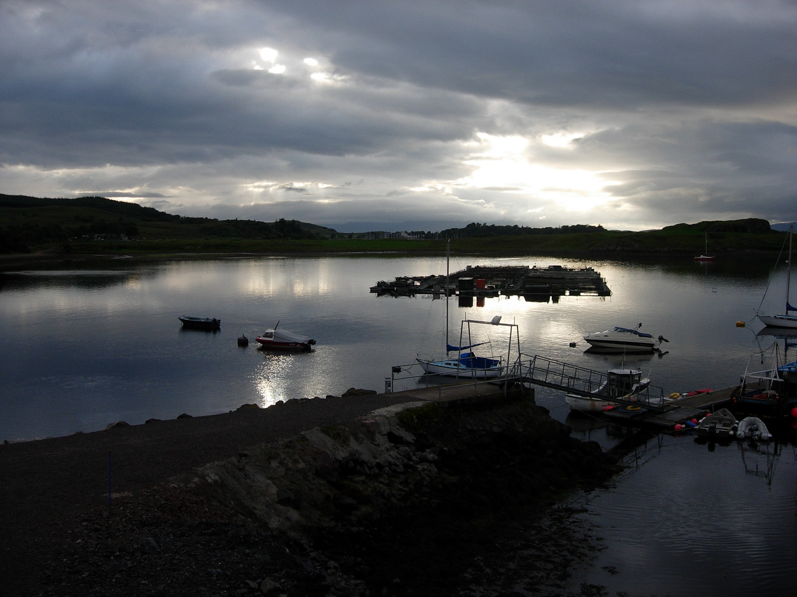 Loch and Boats | Messages From Heroes Boats are docked on a calm loch under cloudy skies, reflecting the long service of frontline workers.