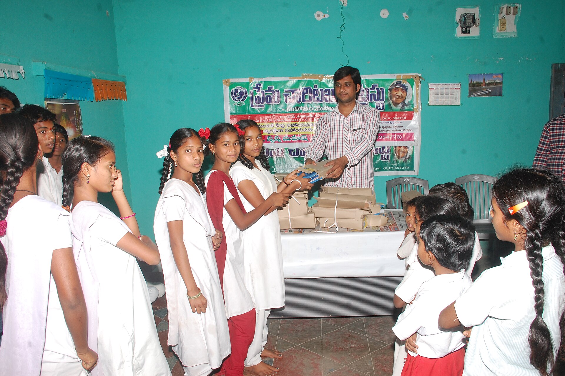 Social Workers & Advocacy | Heroes Messages Stories A man presents a gift to schoolchildren at an indoor event, highlighting service and gratitude.